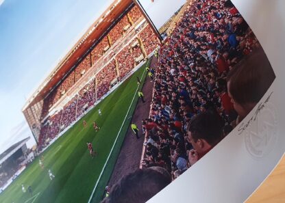 A photograph of Pittodrie Stadium taken from Section Y shoing a game in action with a fully packed stadium during sunset