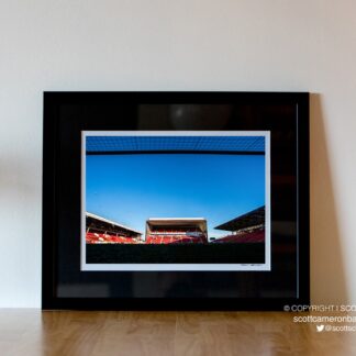 A photograph of a framed limited edition print called Pittodrie Bar. Shoing a photograph taken in the goal mouth with the goal posts bar on show at the top of the picture. taken at Pittodrie Stadium.