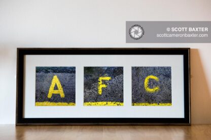 Picture of a 3 aperture frames with square prints displaying A F C yellow painted step markers in a black frame with white mount.