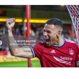 Aberdeen FC striker CHristian Ramirez celebrates a goal raising his arm and shouting at the crowd.